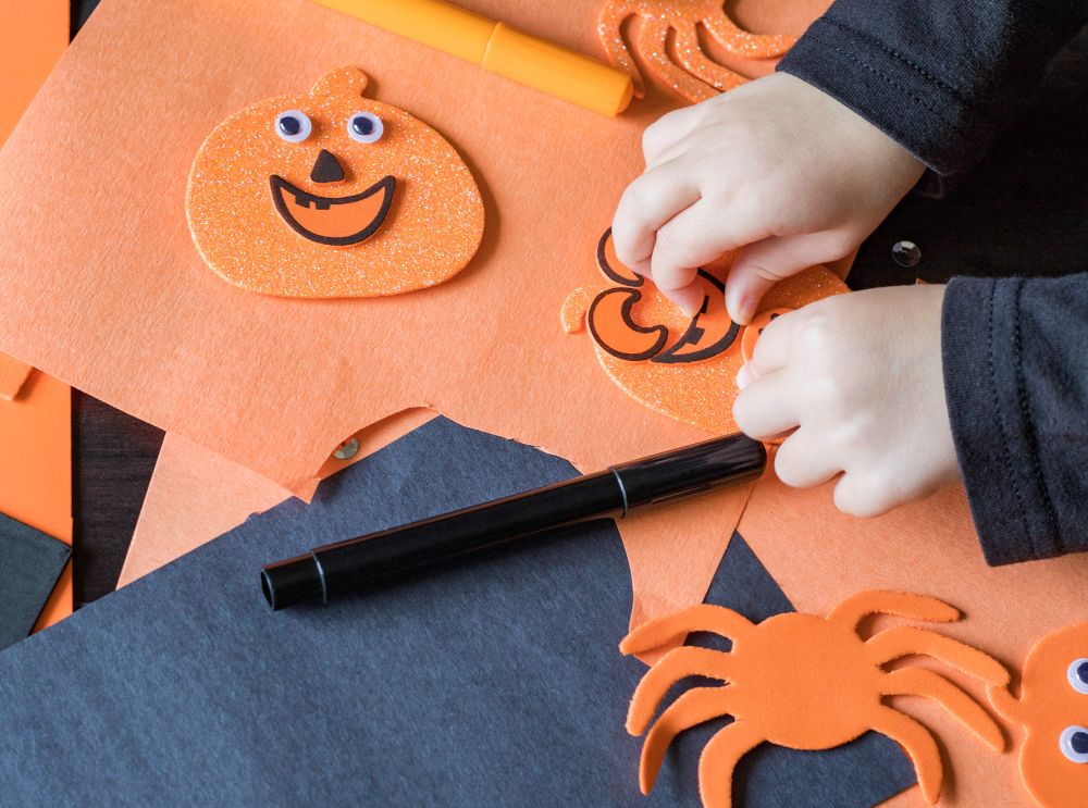 Barn som lager halloween dekorasjoner med orange papp
