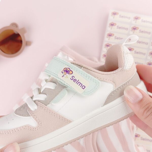 Navnelapp med fantus motiv og lilla tekst som er festet på sko